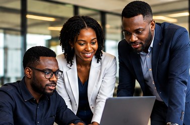Black professionals collaborating around a laptop in a modern office